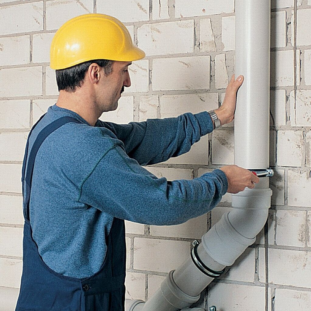 Handwerker arbeitet an Abwasserrohr
